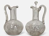 two clear glass vases with handles and handles on a white surface