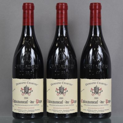 three bottles of red wine sitting on top of a glass table