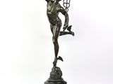 statue en bronze représentant un homme tenant un oiseau, posée sur un socle