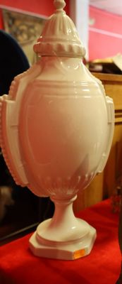 un vase blanc posé sur une nappe rouge, à côté d'une horloge