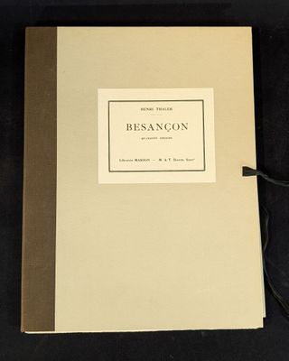 an old book sitting on top of a black table next to a pair of scissors