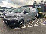 une camionnette grise garée sur un parking, avec d'autres camionnettes en arrière-plan