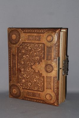 an old book with a decorative design on it sitting on top of a table