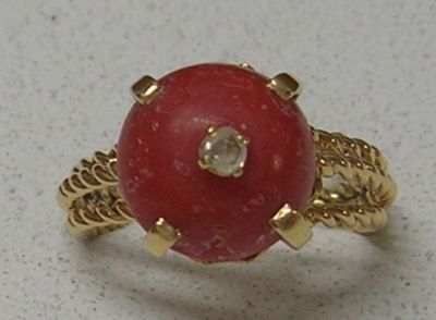une photo d'une bague sertie d'une pierre rouge et d'un diamant
