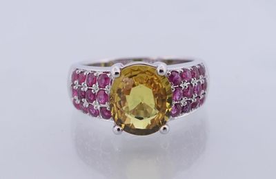 un gros plan d'une bague ornée d'une pierre jaune entourée de pierres roses