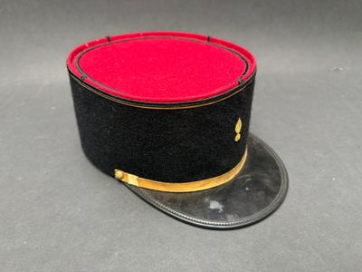 chapeau haut-de-forme noir et rouge avec des bordures dorées sur un fond gris