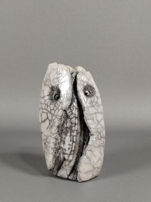 un gros plan sur une sculpture représentant deux oiseaux posés sur une surface grise
