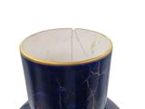 a blue and gold cup and saucer on a white surface