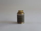 un petit briquet en argent et en or posé sur une surface blanche