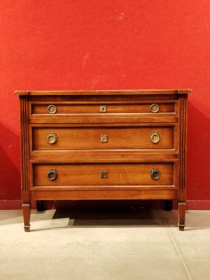une commode en bois devant un mur rouge