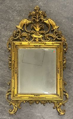 un miroir au cadre doré ouvragé accroché à un mur sur fond blanc