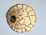 une broche en or ornée de perles, posée sur un fond blanc
