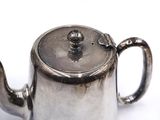a silver tea pot on a white surface