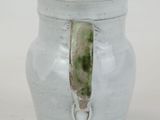 a white vase with a green handle sitting on a table