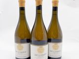 trois bouteilles de vin blanc posées sur une table blanche