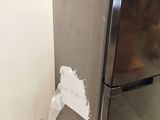 a picture of a stainless steel refrigerator in the corner of a room