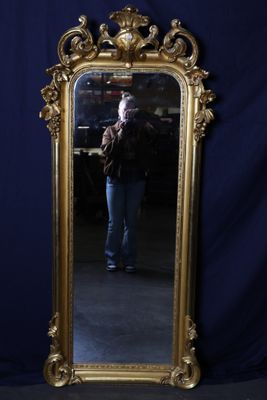 un miroir à cadre doré dans lequel une femme se prend en photo