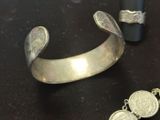 two silver bracelets and a silver ring on a table