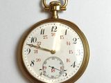 a close up of a gold pocket watch on a white surface