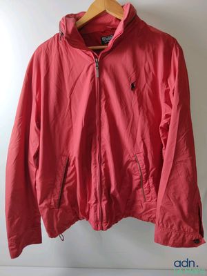 a red jacket hanging on a hanger in front of a white wall