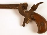 un vieux pistolet avec une poignée en bois sur une surface blanche