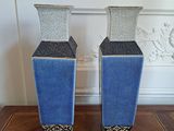 two blue vases sitting on a table in front of a white wall