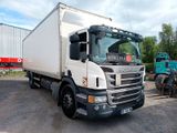 un camion blanc garé sur un parking, avec d'autres camions en arrière-plan