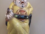 une figurine représentant un homme assis sur une chaise, tenant un téléphone portable