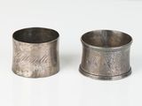 une paire de porte-serviettes anciens en pewter posés sur un support blanc