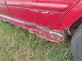 une voiture rouge qui a été endommagée et qui est garée dans l'herbe