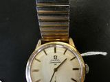 une montre en or avec un cadran blanc sur un fond noir