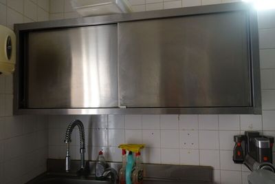 un évier en acier inoxydable dans une cuisine, avec un micro-ondes au-dessus