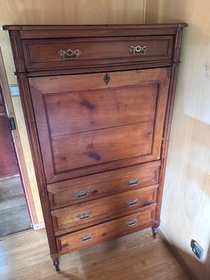 a tall wooden dresser in the corner of a room