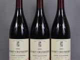 three bottles of red wine are lined up on a glass table