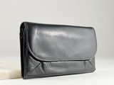 La pochette en cuir noir est posée sur une dalle de marbre