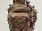 a vase that has a bird on it on a stand