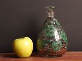 an apple next to a glass bottle on a table