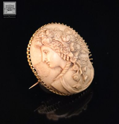 une broche ancienne en ivoire sculpté, ornée d'une tête de femme