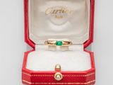 a gold ring with a green stone in a red box