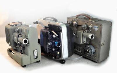 trois vieilles caméras de cinéma posées les unes à côté des autres sur une table