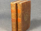 two old books sitting on top of each other on a table