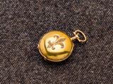 une image représentant une montre de poche en or posée sur un tissu noir