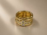 gros plan d'une bague en or avec des diamants sur une surface blanche