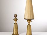 une paire de lampes de table en laiton avec des abat-jours en plis, posées sur une surface blanche