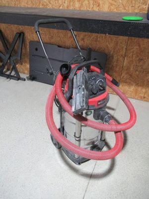 un aspirateur posé par terre, muni d'un tuyau rouge
