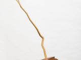 a brown vase with a branch sticking out of it sitting on top of a white pedestal