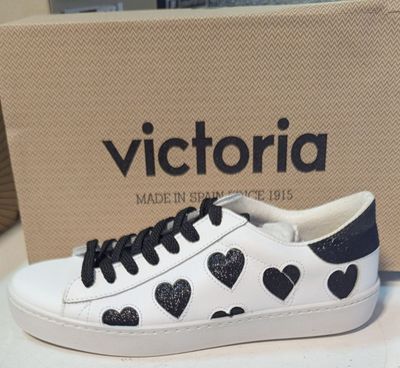 des baskets blanches et noires ornées de cœurs noirs, posées sur une table