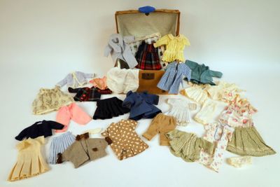 une valise remplie de vêtements et des vêtements posés sur une surface blanche