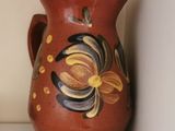 a red vase sitting on a shelf next to a glass