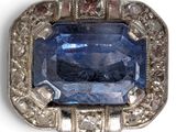 a close up of a blue sapphire and diamond broochle on a white background